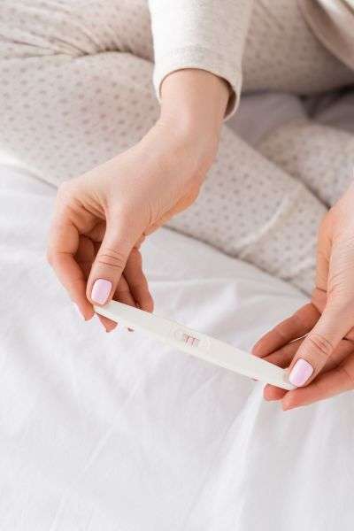 Early Signs of Pregnancy image of womans hands holding a positive pregnancy test.