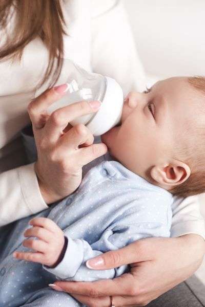Mom feeding her baby a bottle of formula.