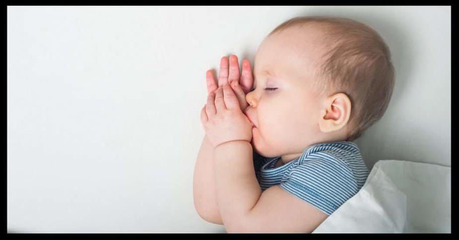 Baby sleeping in crib sucking his thumb. 