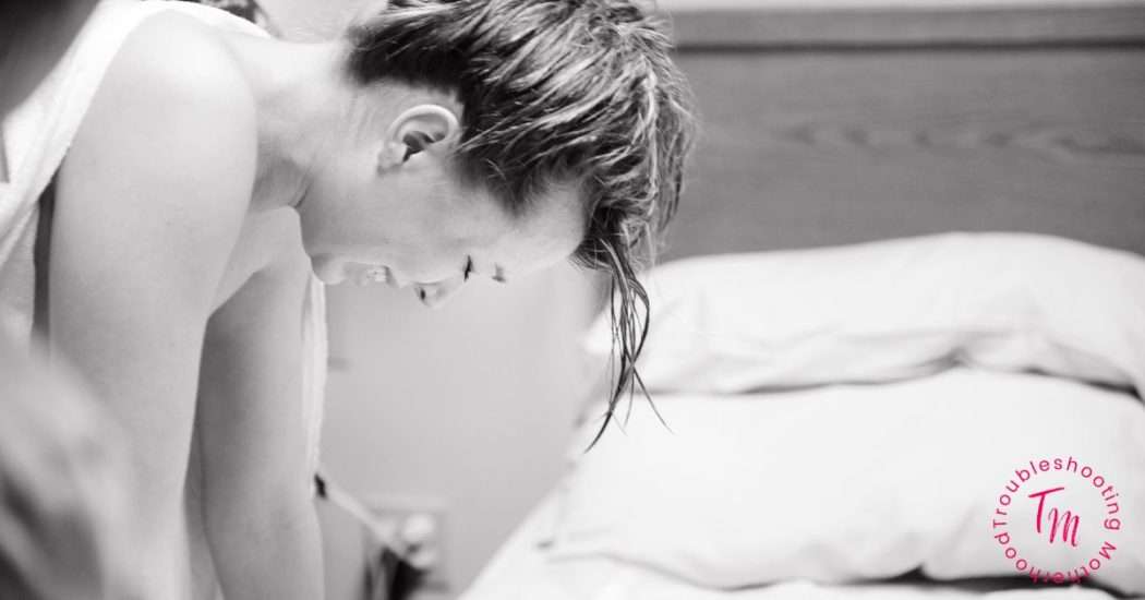 The best labor advice i ever got. Black and white image of woman in labor leaned over a bed.