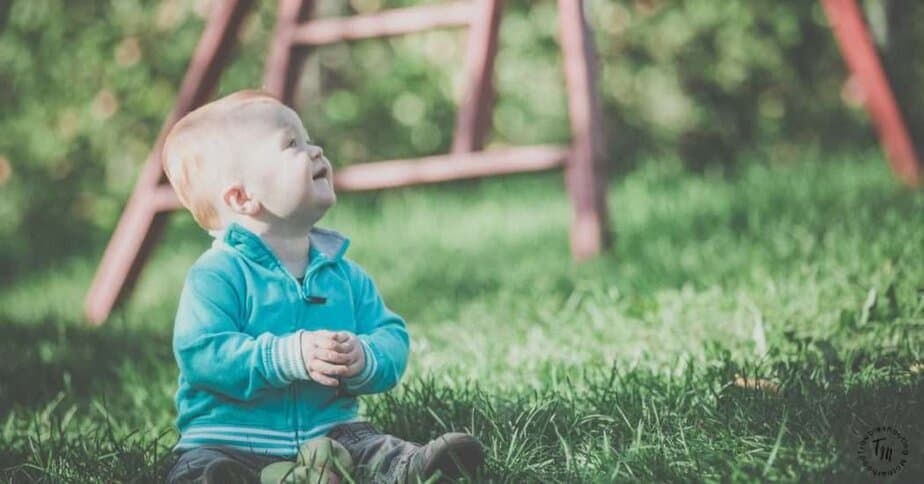 Earthy Boy Names. Image of baby boy sitting in the grass.