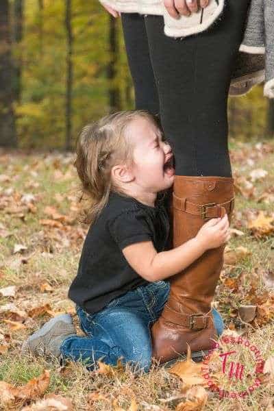 How to Diffuse toddler tantrums. Image of toddler grabbing onto moms legs, crying.