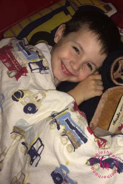 Help Kids Fall Asleep Fast. Image of toddler boy laying in bed, smiling. Good parenting. Toddler Bedtime. Deep Breathing. Mommy Tips.
