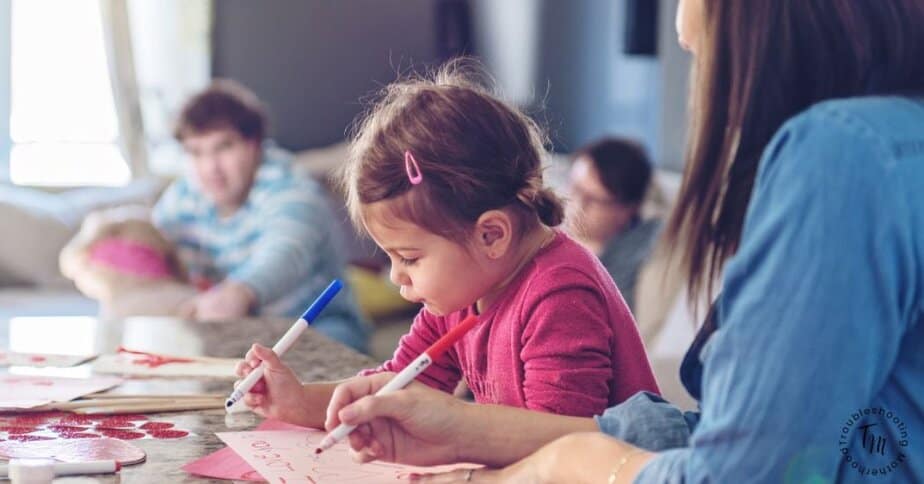 Child working on candy free Valentines for classroom exchange with markers and handmade cards. Non Candy Valentines for Classroom parties. 